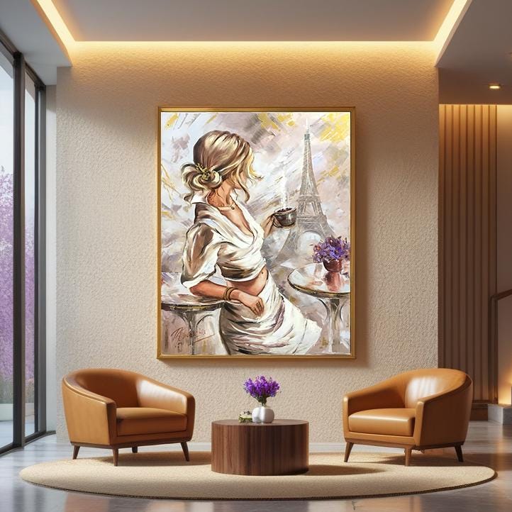 A framed oil painting depicting a woman in a white dress with the Eiffel Tower in the background, displayed on a wall in a modern living room setting with two brown leather armchairs and a small wooden coffee table.