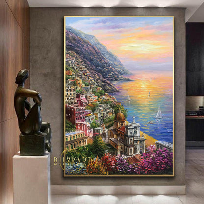 May include: Oil painting of a coastal town with colorful buildings cascading down a hillside to the sea. The artwork features a sunset with warm hues, sailboats, and the text "BIIVKART" in the lower left corner.